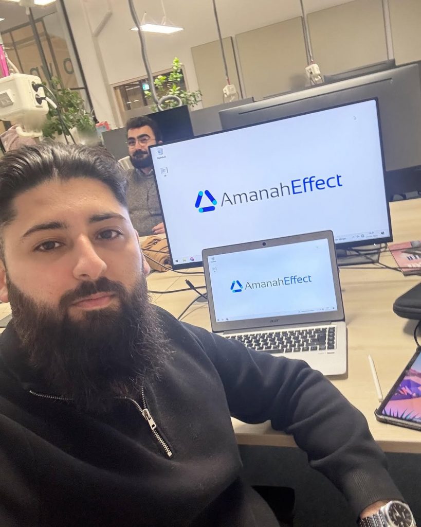 Maziar arbeitet am Computer mit Amanaheffect Branding im Hintergrund.